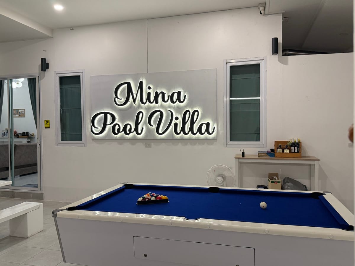 Full-size pool table and the illuminated Mina Pool Villa sign in the games area