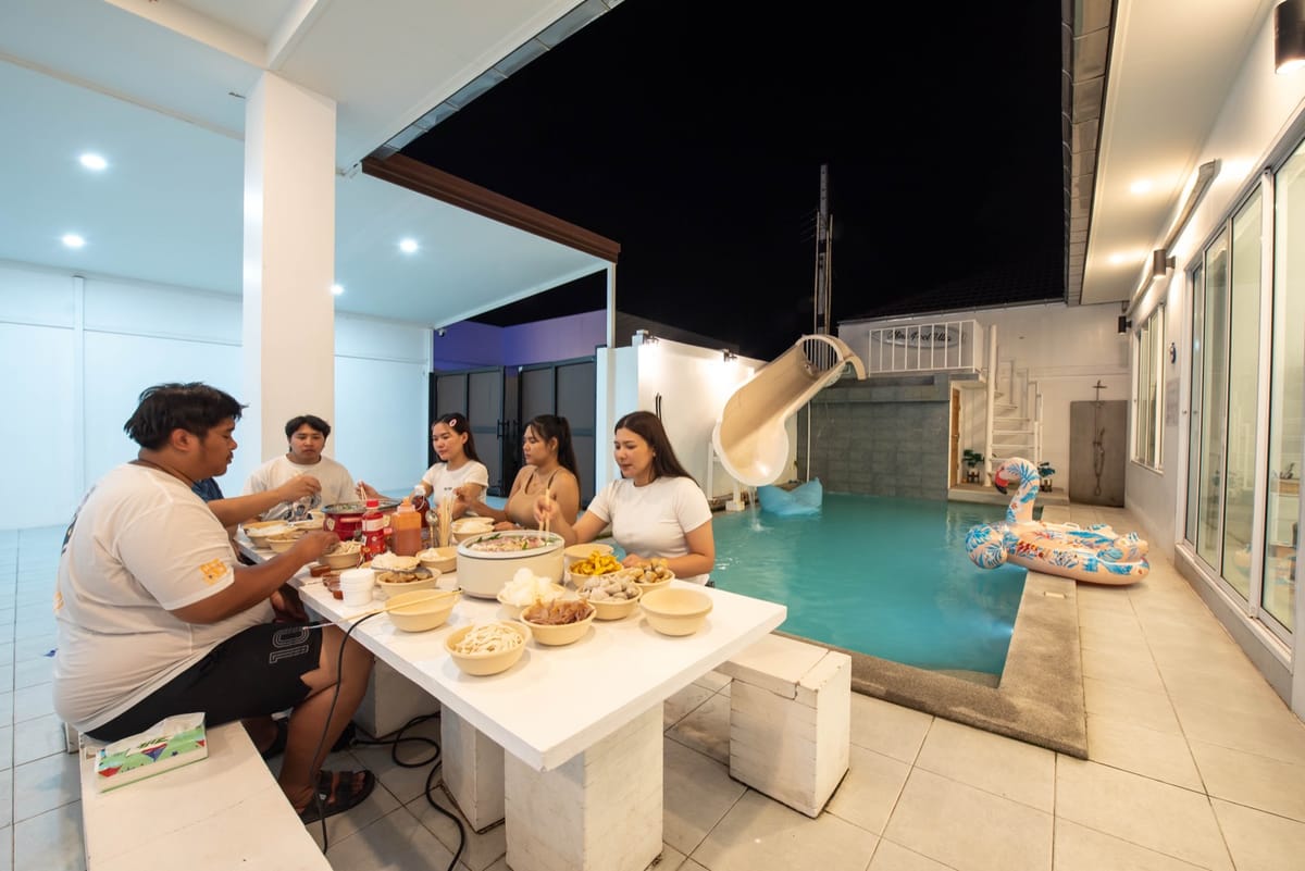Guests dining together at the outdoor table beside the pool