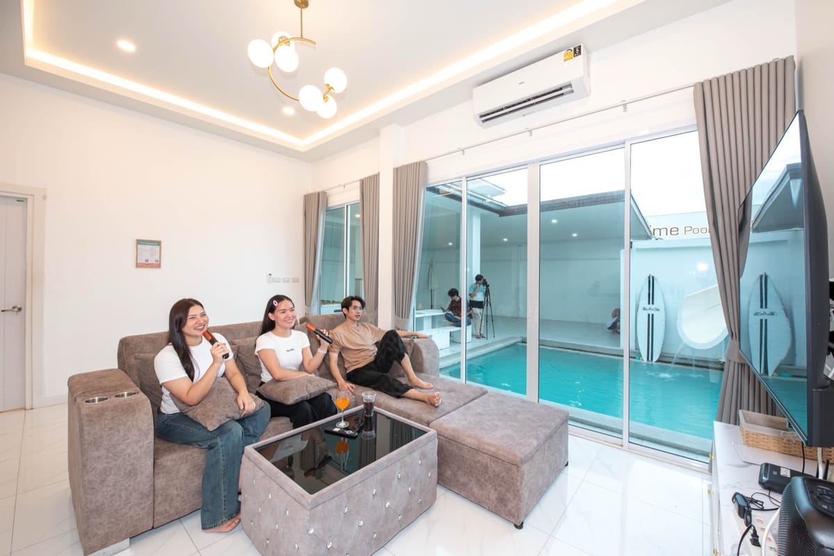 Living room with sofa and floor-to-ceiling glass doors onto the pool